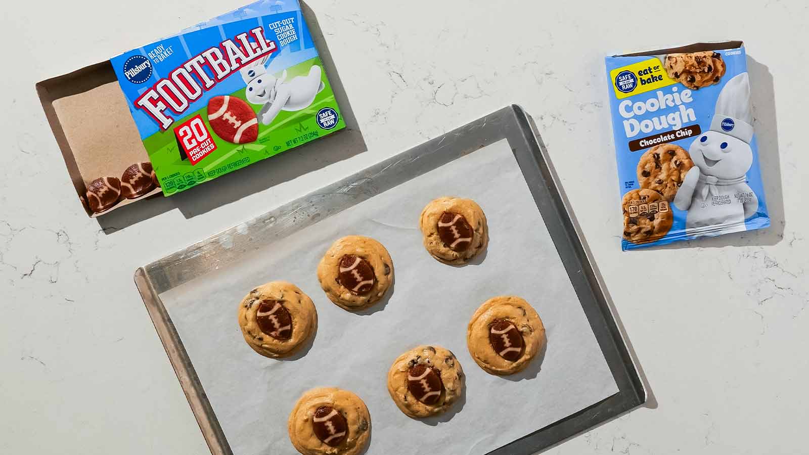Baking sheet with double stacked cookies made with chocolate chip cookie and football shape dough.