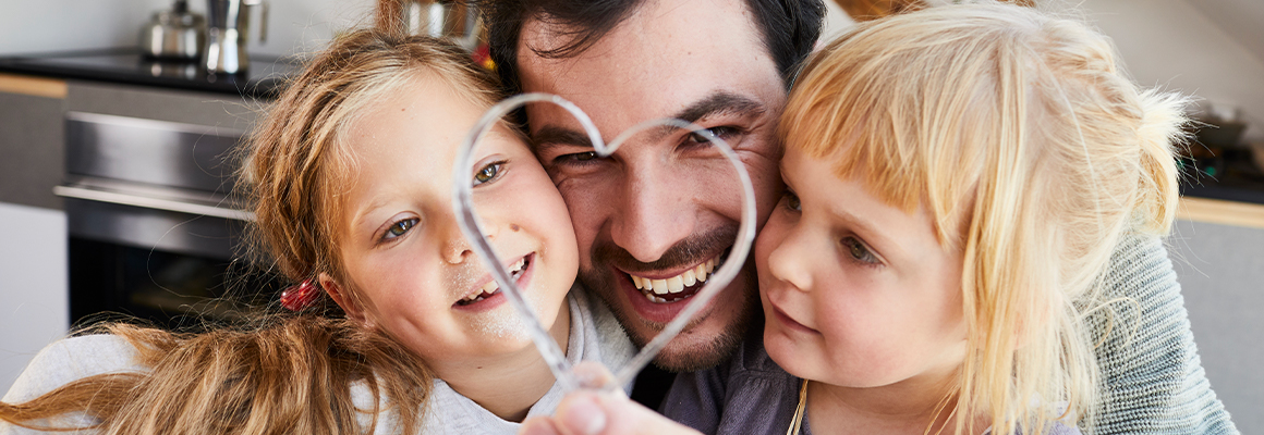 Dad and 2 daughters with a heart cookie cutter