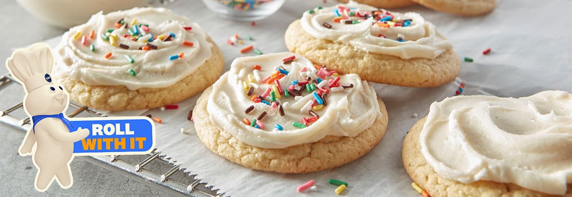 Cookies with white frosting and colorful sprinkles on a cooling rack. 
